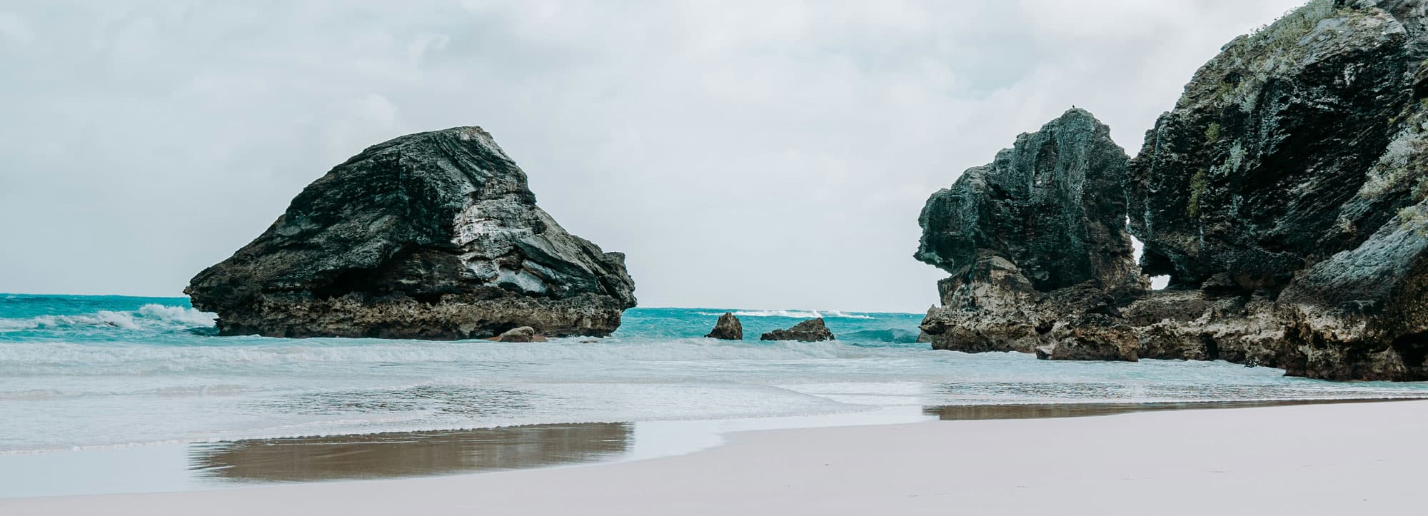 The Bermuda coast: limestone rock stacks in turquoise water off a pink sand beach.